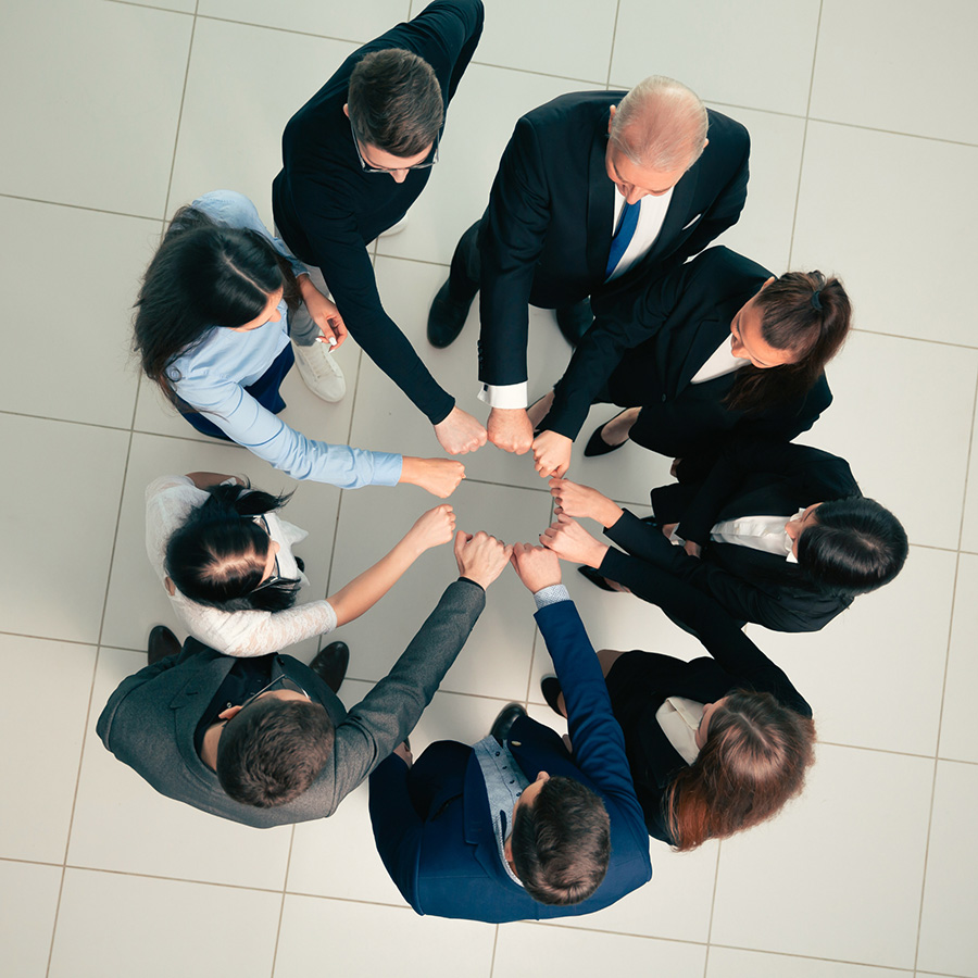 Gruppo di professionisti in cerchio che uniscono i pugni in segno di collaborazione