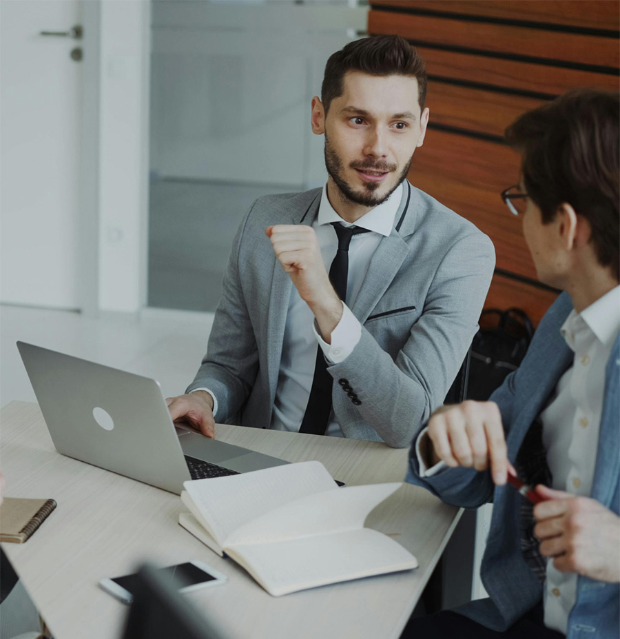 Due professionisti discutono durante una riunione di lavoro con laptop