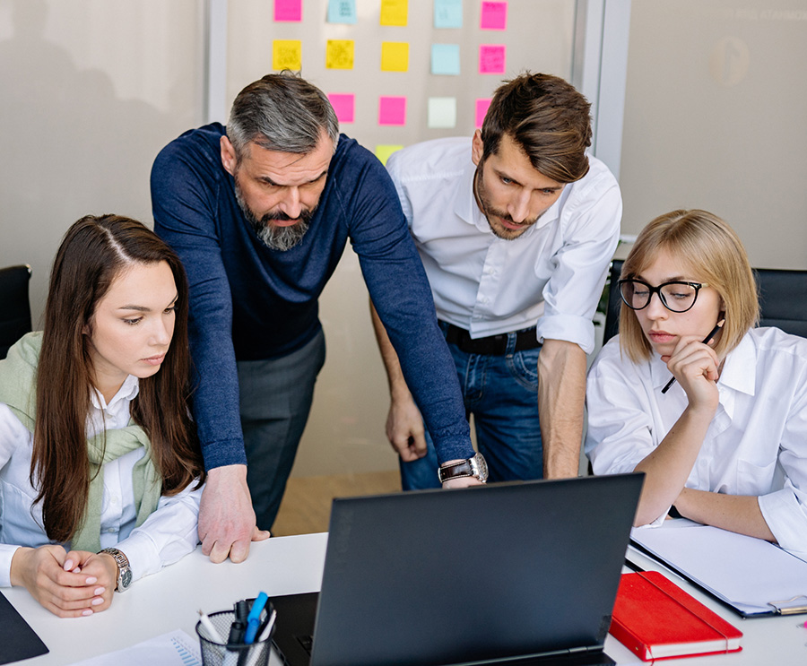 Team di professionisti riuniti intorno a un laptop durante una riunione